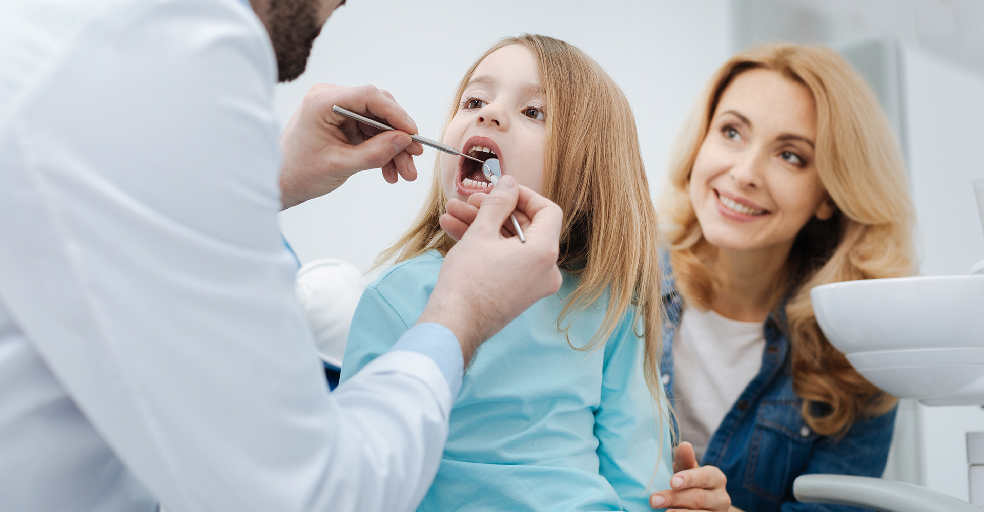 Dentiste examinant les dents d’une enfant avec sa maman